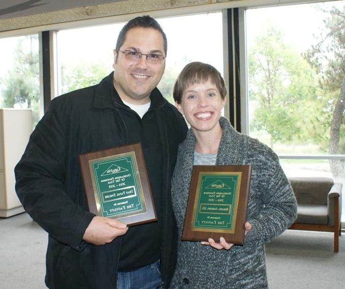 Two professors holding awards